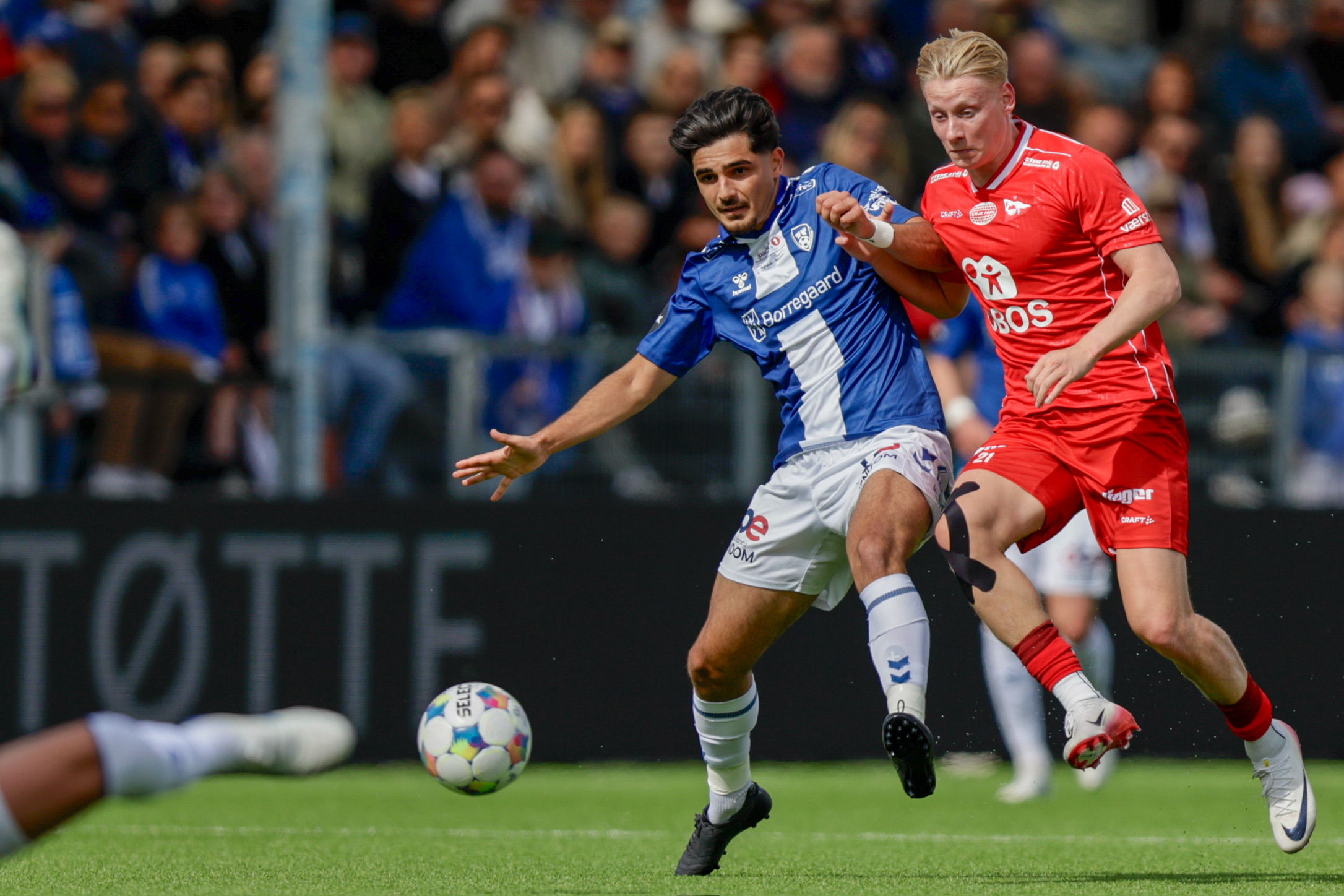 Fotballspillere i blått og rødt i løpsduell